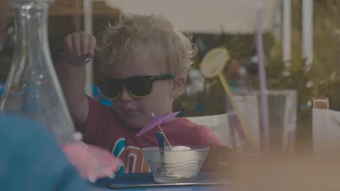 Young toddler sitting at table with sun glasses, sunny day Stock Footage 88903769