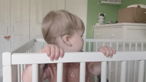 Young toddler standing in crib looking at camera 4k Stockbeeldmateriaal 342776912