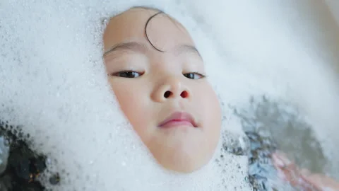 Young toddler's face emerges from thick soap bubbles in a bathtub Stock Footage 339047501