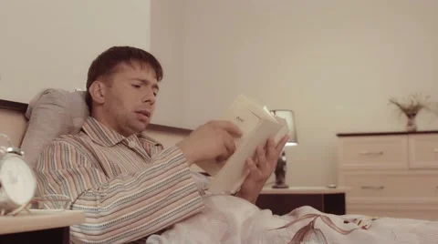 Young touched man reading a touching book almost crying Stock-Footage 68420738