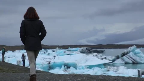A young tourist getting to know the frozen lake of Jökulsárlón Stock Footage 130895413