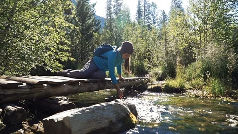 Young tourist in a hat with backpack is drinking from the cold mountain creek Stock Footage 96441335