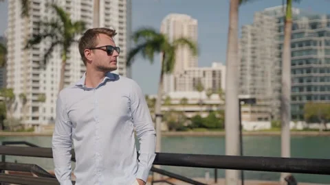 Young tourist man using smartphone with Brickell Bay Miami skyline, sunny day 動画素材 318535577