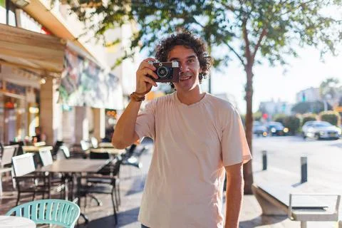Young tourist smiling happily using camera during city walk. Photographer tak Stock Photos