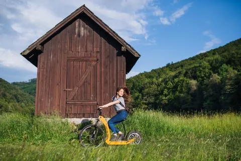 Young tourist woman traveller with electric scooter in nature. Stock Photos