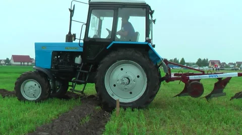 Young tractor operator plows the site in rain Stock Footage 64543212