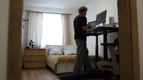 Young trader takes notes and studies charts while walking on a treadmill Stock Footage 346881960