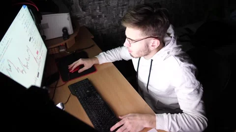 Young trader working on computer at night. Male broker analyzing graphs Stock Footage 306582230