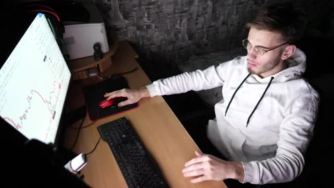 Young trader working on computer at night. Male tired broker analyzing graphs Stock Footage 315436240