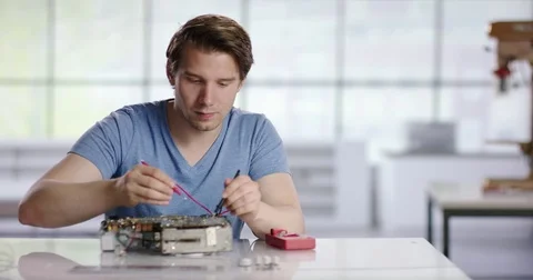 Young trainee testing solder points on old radio Stock Footage 78577128