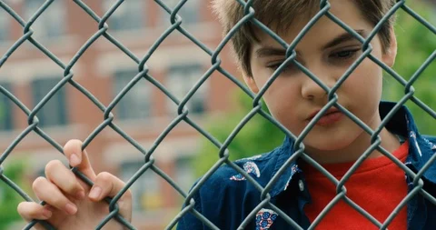 Young transgender boy looking through a chain link fence Stock Footage 108789606