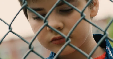 Young transgender boy looking through a chain link fence Stock Footage 108789839