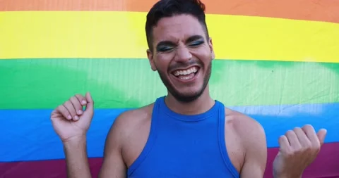 Young transgender man with make up dancing in front of rainbow flag Stock Footage 158222007