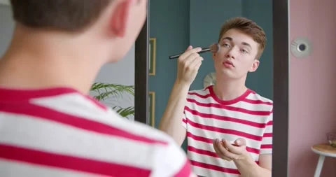 A young transgenger man does a make up, applying powder with a brush Stock Footage 134977688