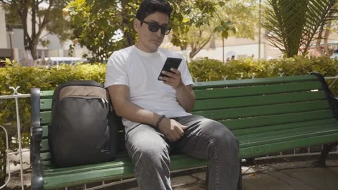 Young traveler checking his cell phone in a public square Stock Footage 273586162
