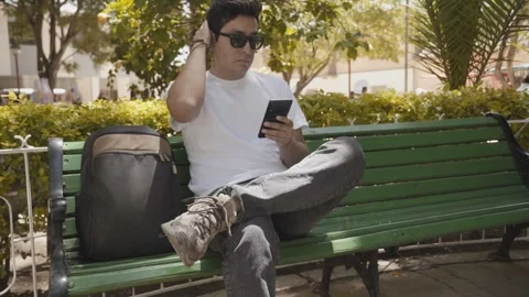 Young traveler checking his cell phone in a public square Stock Footage 273586558