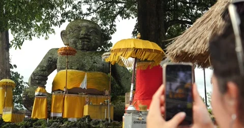 Young traveler makes a video of a large baby statue in bali indonesia Stock-Footage 242501839