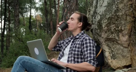 Young traveling man with backpack using laptop to work remotely in forest. Stock Footage 151859952