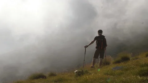 Young trekker man standing on the mountain in the fog with backpack, boots and Stock Footage 143901006