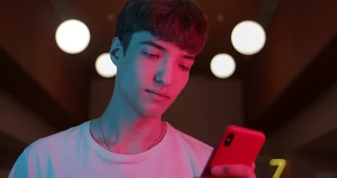 Young Trendy Guy in White T-Shirt Using his Modern Smartphone while Standing at Stock Footage 119058628
