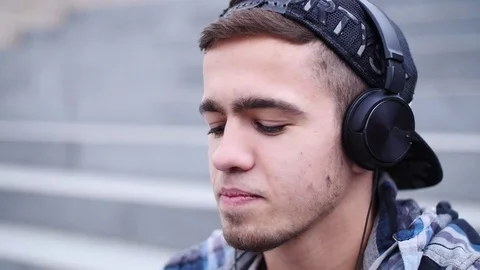 Young trendy man listen to music on smartphone sitting on the steps outdoor Stock Footage 81221253