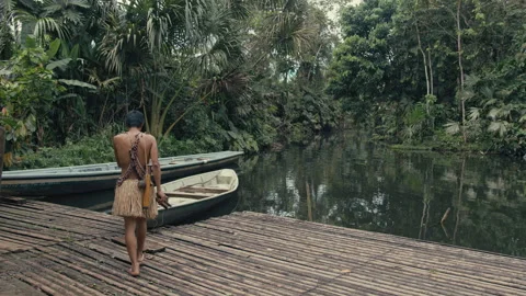 Young tribe man approaching a Canoe in Amazon Stock Footage 270461765
