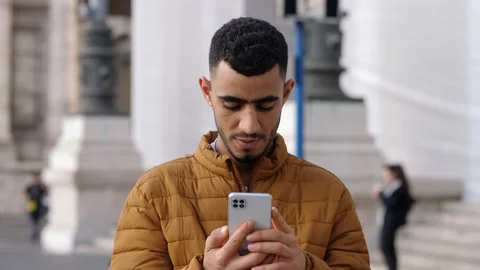 Young tunisian man using his smartphone in the street: technology concept Stock Footage 218583880