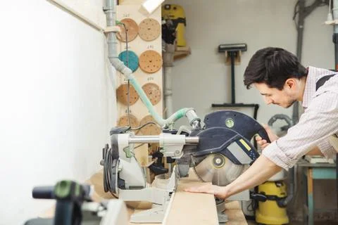 Young turner cuts board with circular saw Foto stock