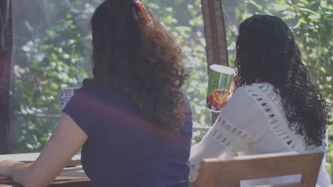 Young twins drinking coffee and laughing at a terrace Stock Footage 80385059