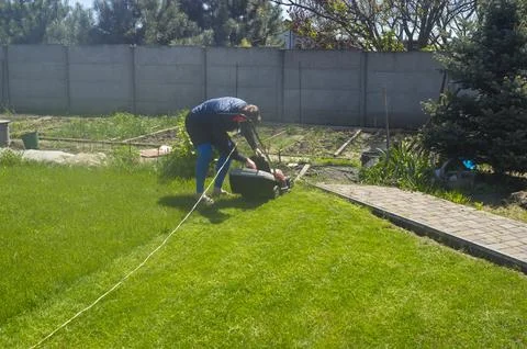 Young Ukrainian man checking package filled with cut grass when cut lawn with Foto stock