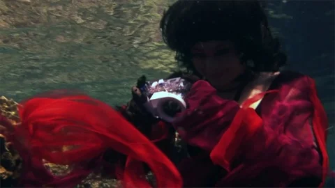 Young underwater model free diver in red dress photographs on camera in Red Sea. Video stock 73297625