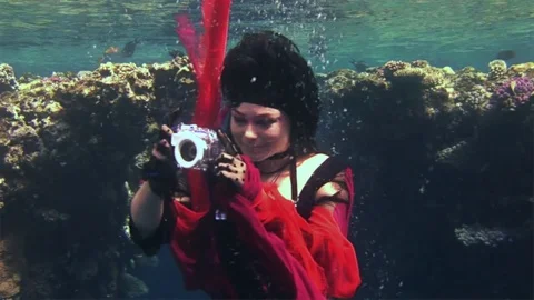 Young underwater model free diver in red dress photographs on camera in Red Sea. Video stock 73297683