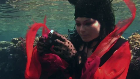 Young underwater model free diver in red dress photographs on camera in Red Sea. Video stock 73461033