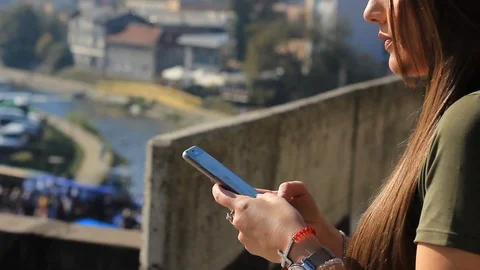 Young unhappy brunette typing a message on the smartphone, on the bridge Stock Footage 121315411