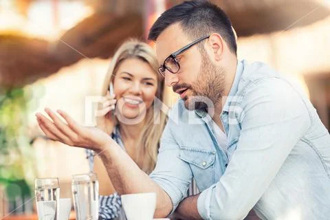 Young unhappy man and his girlfriend who uses the phone Stock Photos