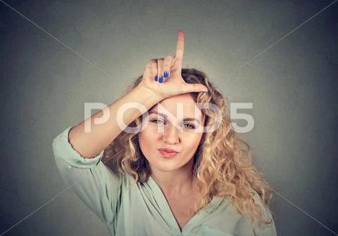 Young unhappy woman giving loser sign on forehead Stock Photos