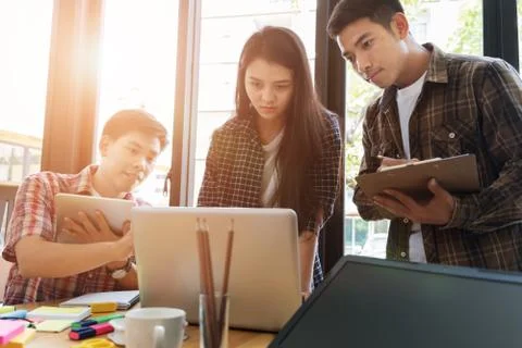 Young university students studying with computer and tablet in cafe. Group .. Stock Photos