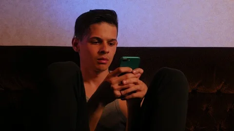 Young upset man using smartphone in the room Видео 106370562