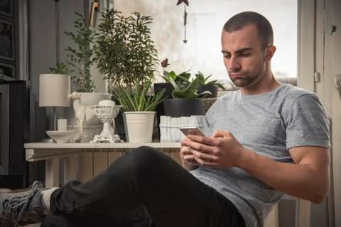 Young an using his cell phone at home Stock Photos