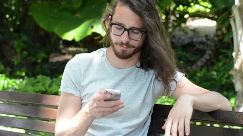 Young using the phone in a park. Middle twenties. Long hair and blue  eyes Stock-Footage 63539232