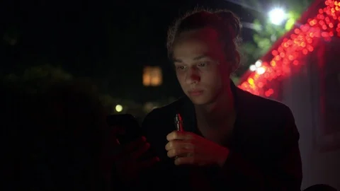 Young vaping man illuminated of red light outdoors at night 3 Stock Footage 95861253