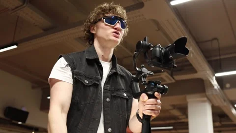 Young videographer dances and demonstrates shooting moves while holding camera o Stock Footage 332116845