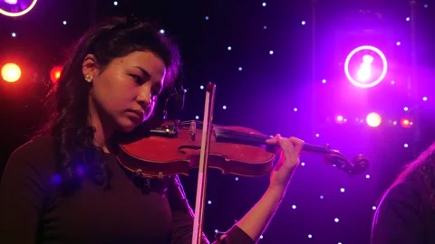 Young violinist performing on stage with dramatic lighting during a live concert Vidéo 303132158