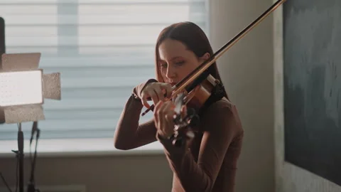 Young violinist practicing. Indoor sunlit space for practicing violin. Young Stock Footage 346555733