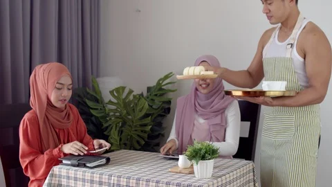 Young waitress man serve brought coffee to two muslim woman Stock Footage 123330615