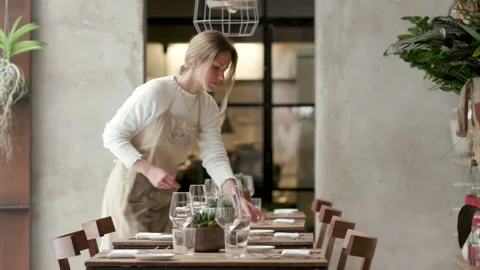 Young waitress preparing and laying the table in the restaurant. The girl 動画素材 130384895
