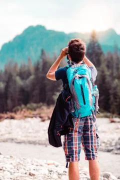 Young wanderer with backpack looks through a binoculars Stock Photos