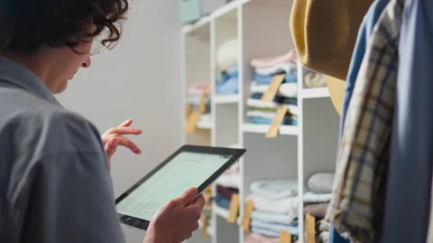 A young warehouse worker keeps track of clothing items using a modern touchs Stock Footage 273743084