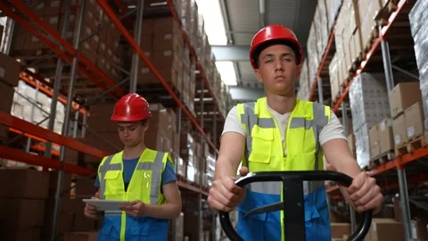 Young warehouse workers walking along aisle Stock Footage 161954672