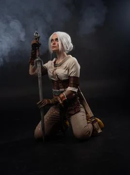 A young warrior with a sword on a dark background. Fantasy heroine Stock Photos